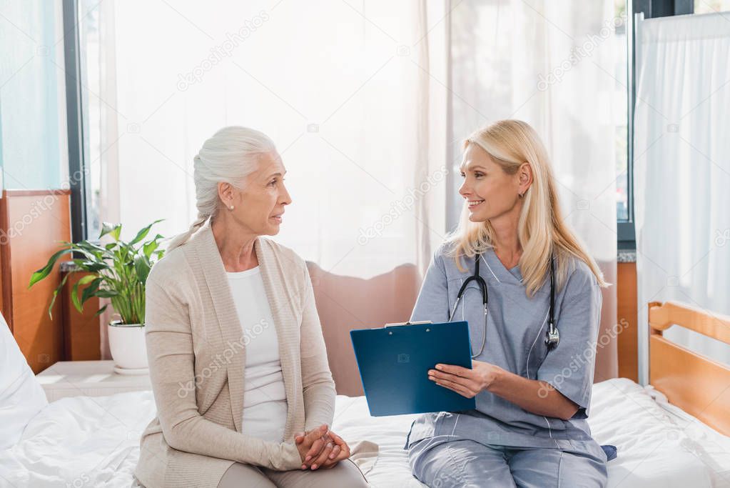 senior woman and nurse with clipboard