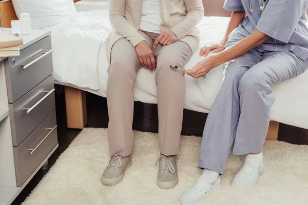 Медсестра вивчає пацієнта з рефлекторним молотком — стокове фото