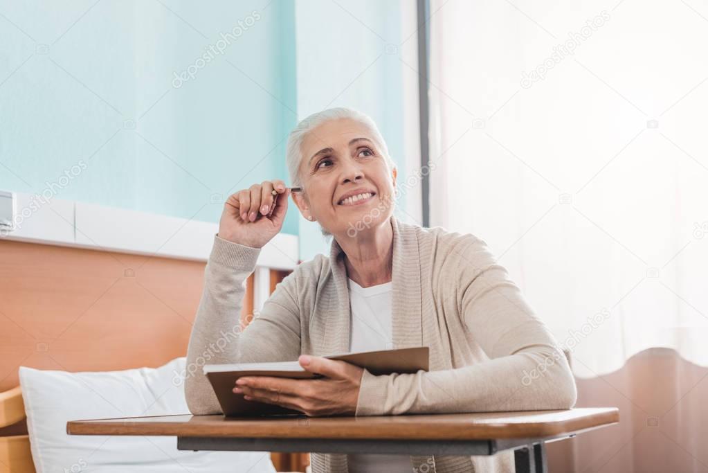 senior woman with notebook in hospital