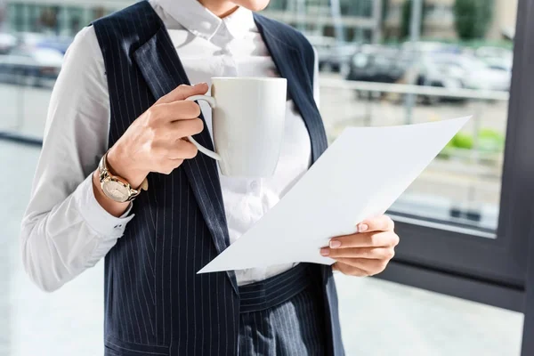 Empresaria sosteniendo papeleo y taza — Foto de Stock