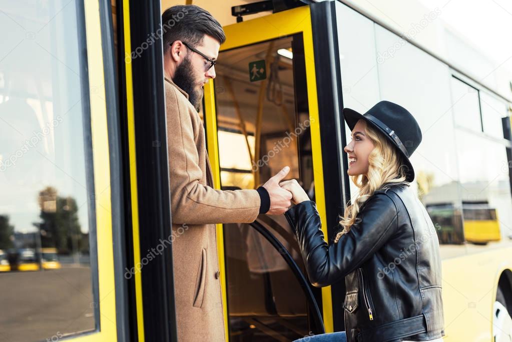 man helping girlfriend to enter bus