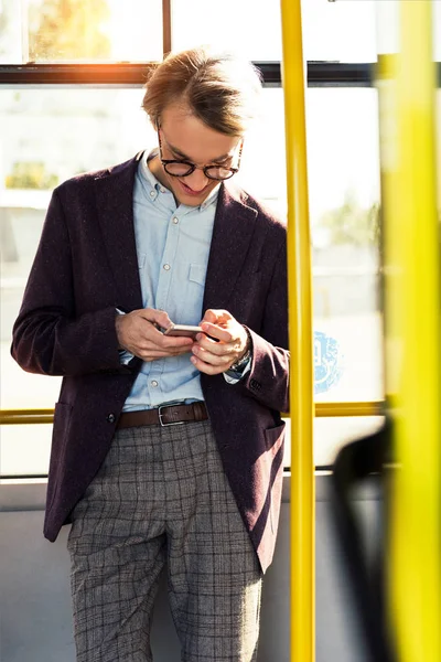 Улыбающийся мужчина со смартфоном в автобусе — стоковое фото