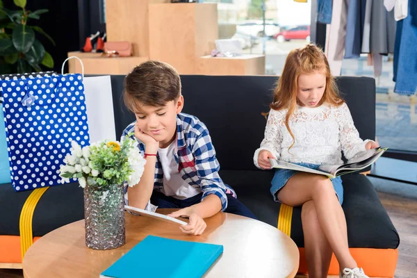 Siblings with magazines in boutique — Stock Photo, Image