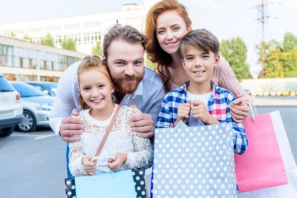 Parents hugging children with shopping bags — Stock Photo, Image