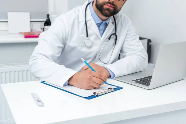 Doctor escribiendo en portapapeles — Foto de Stock