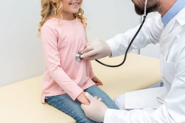 Pediatra escuchando el aliento de una niña — Foto de Stock