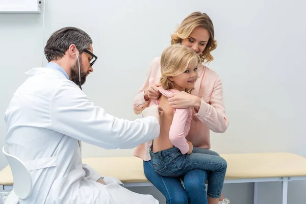 Pediatra escuchando el aliento de una niña — Foto de Stock