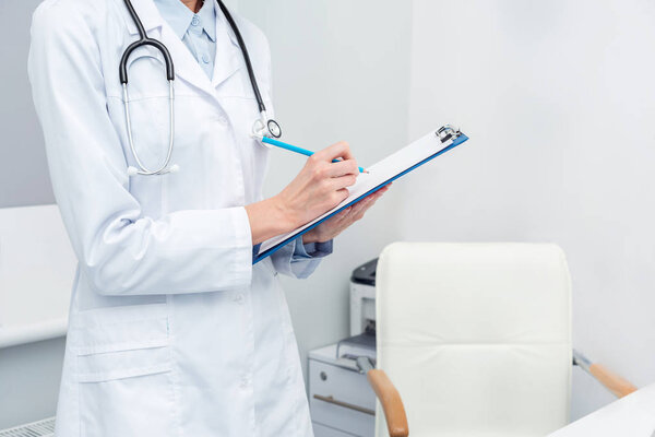 female doctor writing in clipboard