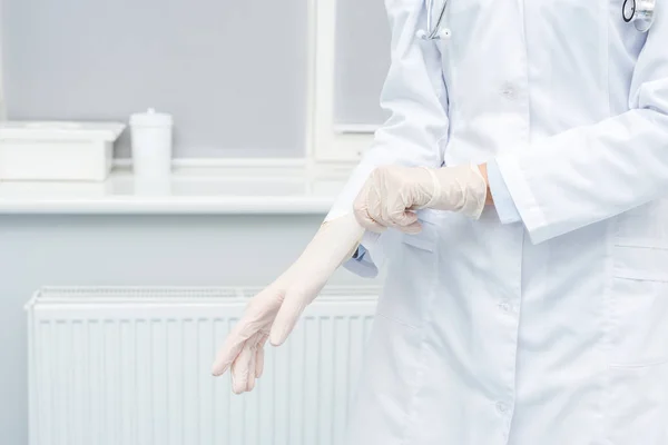 Female doctor putting on gloves — Stock Photo, Image