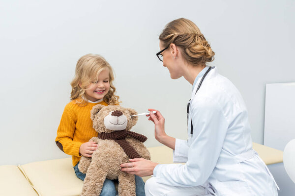doctor measuring temperature of teddy bear