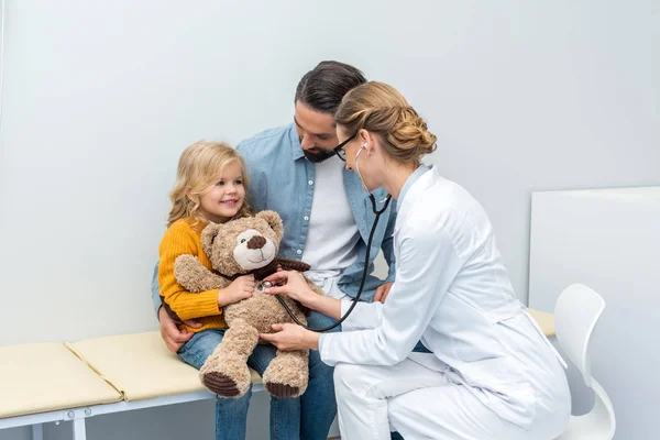 Doctor listening to breath of teddy bear — Stock Photo, Image