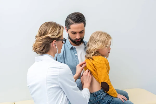 Doctor escuchando el aliento de niña — Foto de Stock