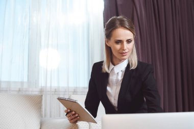 businesswoman taking notes in hotel room clipart