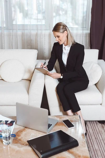 Mujer de negocios tomando notas en la habitación de hotel — Foto de stock gratuita