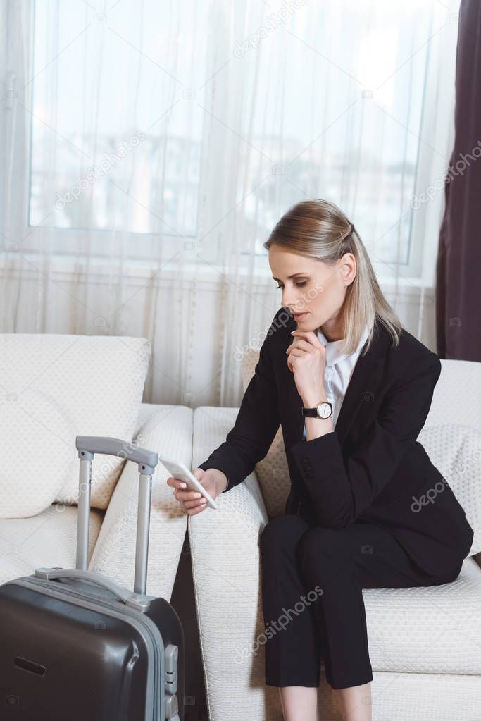 businesswoman with smartphone in hotel room