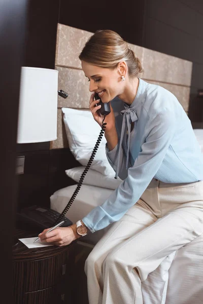 Businesswoman talking by phone in hotel — Stock Photo, Image