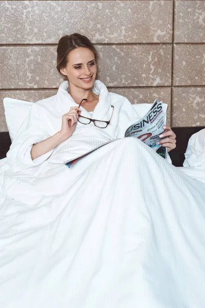 Woman in bathrobe reading magazine — Free Stock Photo