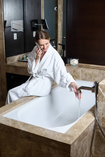 Woman in bathrobe using smartphone — Stock Photo, Image