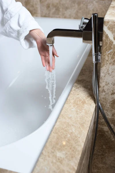 Mujer comprobando el agua en la bañera —  Fotos de Stock