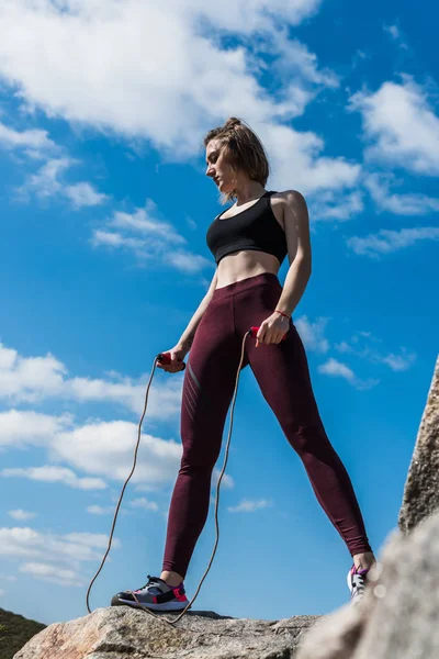 Woman on rock with jumping rope — Free Stock Photo