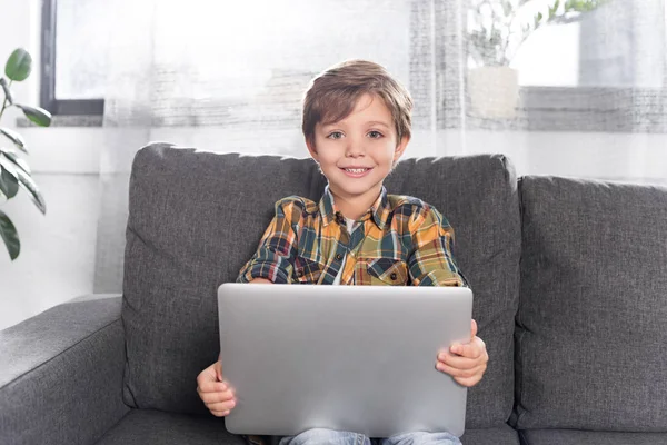 Хлопчик з ноутбуком сидить на дивані — стокове фото