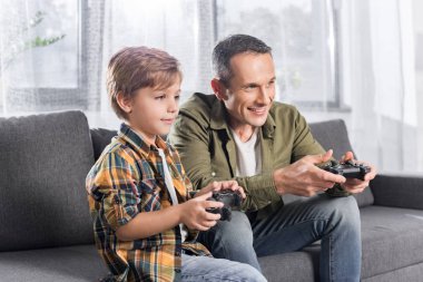 father and son playing console with gamepads clipart
