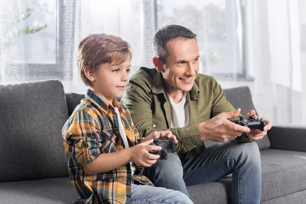 Отец и сын играют на консоли с геймпадами — стоковое фото