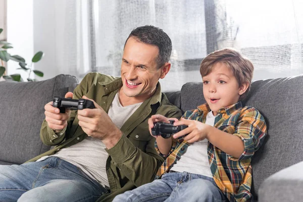 Father and Son Playing Video Games --- Image by © Royalty-…