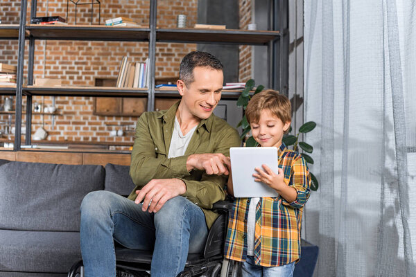 father in wheelchair and son using tablet