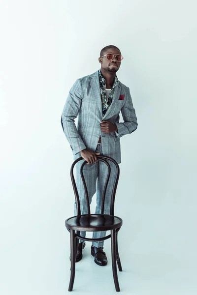 Man in fashionable suit posing with chair — Stock Photo, Image