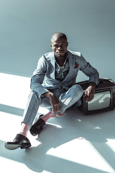 Человек в стильном костюме позирует с телевизором
