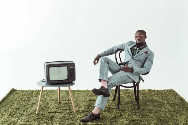Człowiek w okularach słonecznych i garnitur na krześle z tv — Zdjęcie stockowe