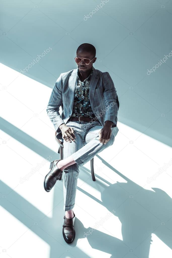 Young man in sunglasses posing on chair