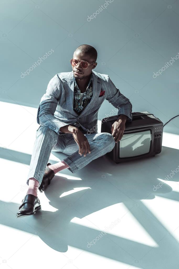 Man in stylish suit posing with tv