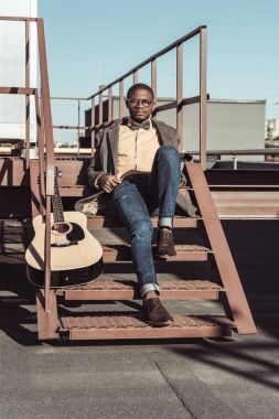 Afrika kökenli Amerikalı adam gitar ile merdivenlerde
