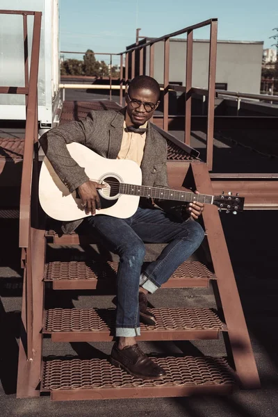 Afrika kökenli Amerikalı adam merdivenlerde gitar çalmak