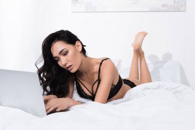 Yatakta dizüstü bilgisayar kullanan kadın