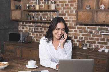 Telefonla konuşurken ve dizüstü kullanan kadın