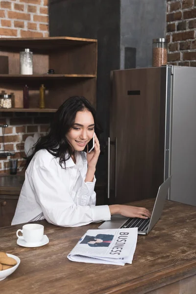 Woman talking by phone and using laptop — Stock Photo, Image