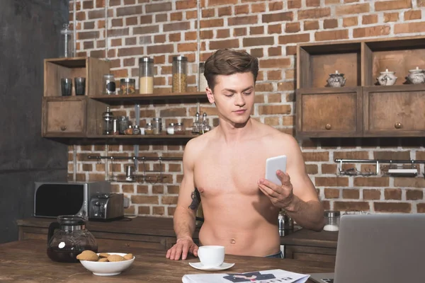Человек с помощью смартфона на кухне — стоковое фото