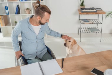 Adam köpeğini sevişme tekerlekli sandalye üzerinde