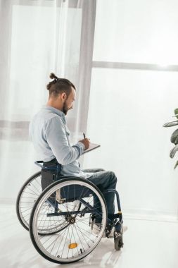 man on wheelchair writing in notebook clipart