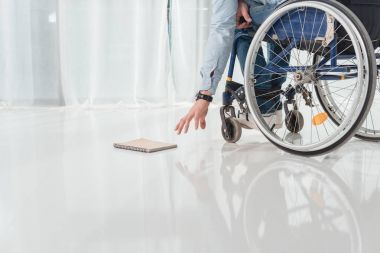 man on wheelchair trying to reach for book clipart