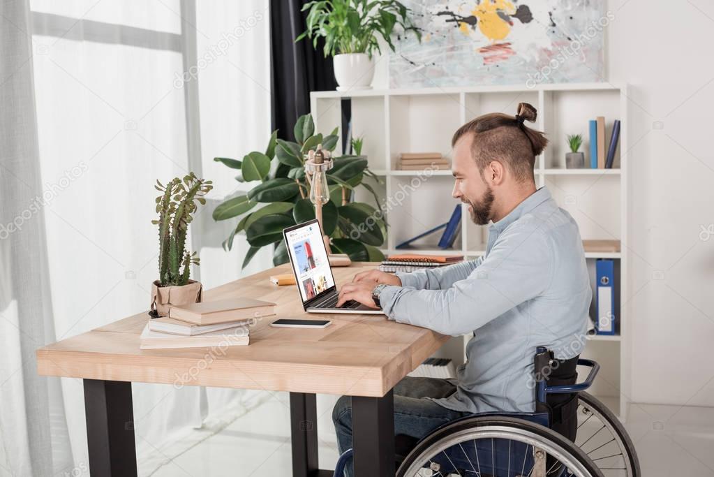 Disabled man on wheelchair using laptop with ebay website