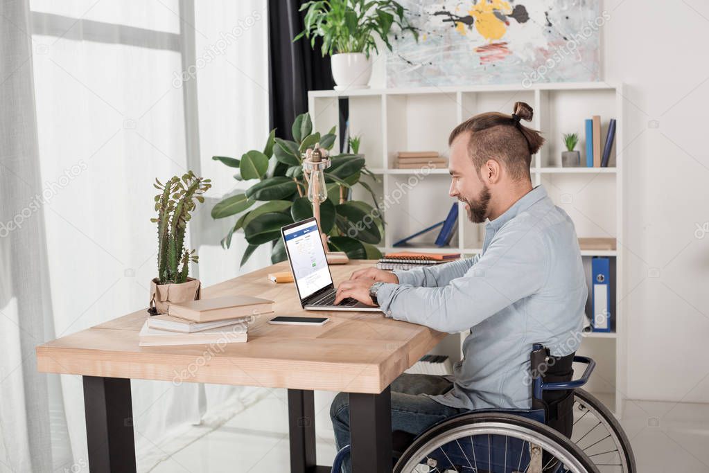 Disabled man on wheelchair using laptop with facebook website