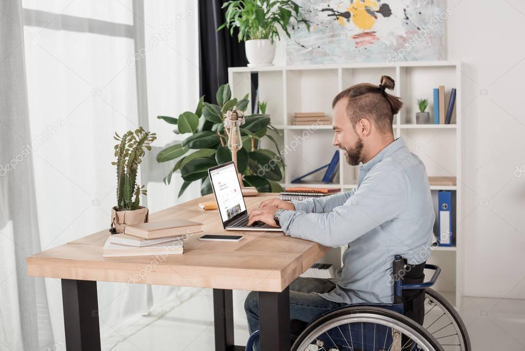 Disabled man on wheelchair using laptop with airbnb website