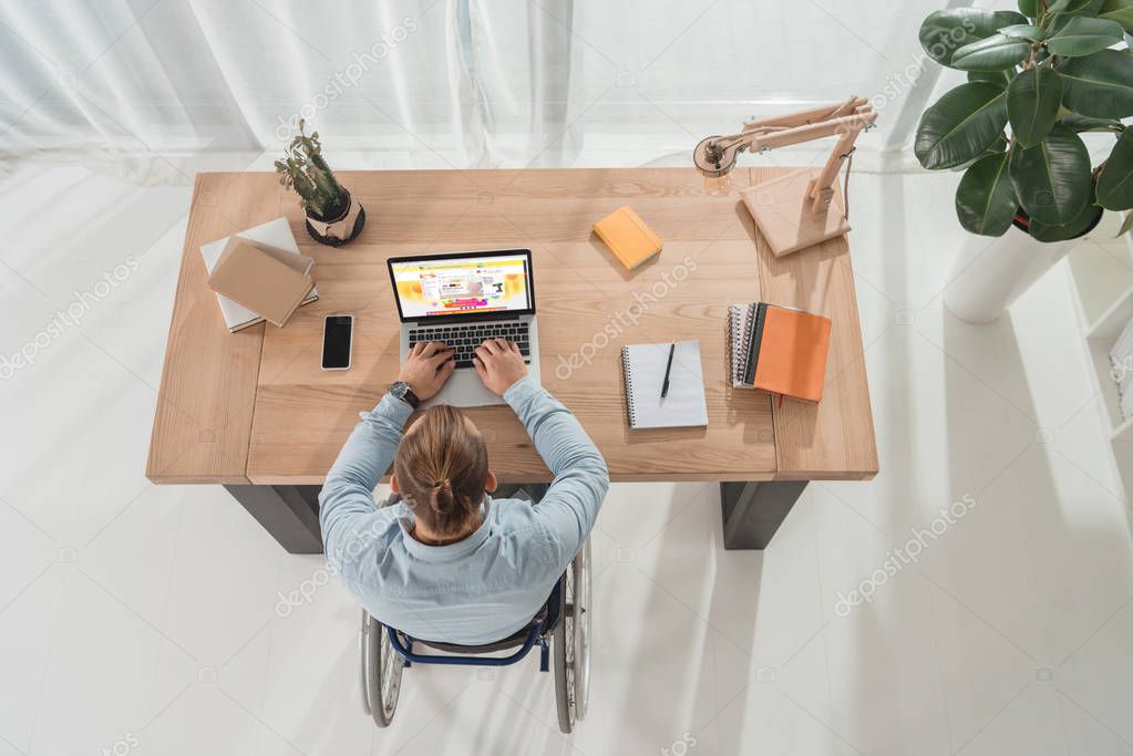 Top view of disabled man on wheelchair using laptop with aliexpress site