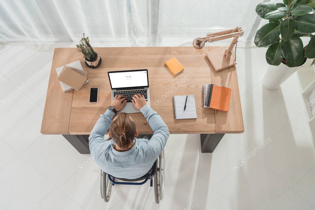 Top view of disabled man on wheelchair using laptop with google website