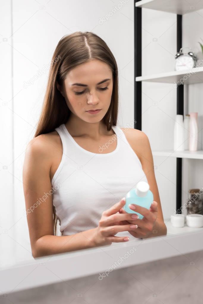 woman looking at bottle of lotion 