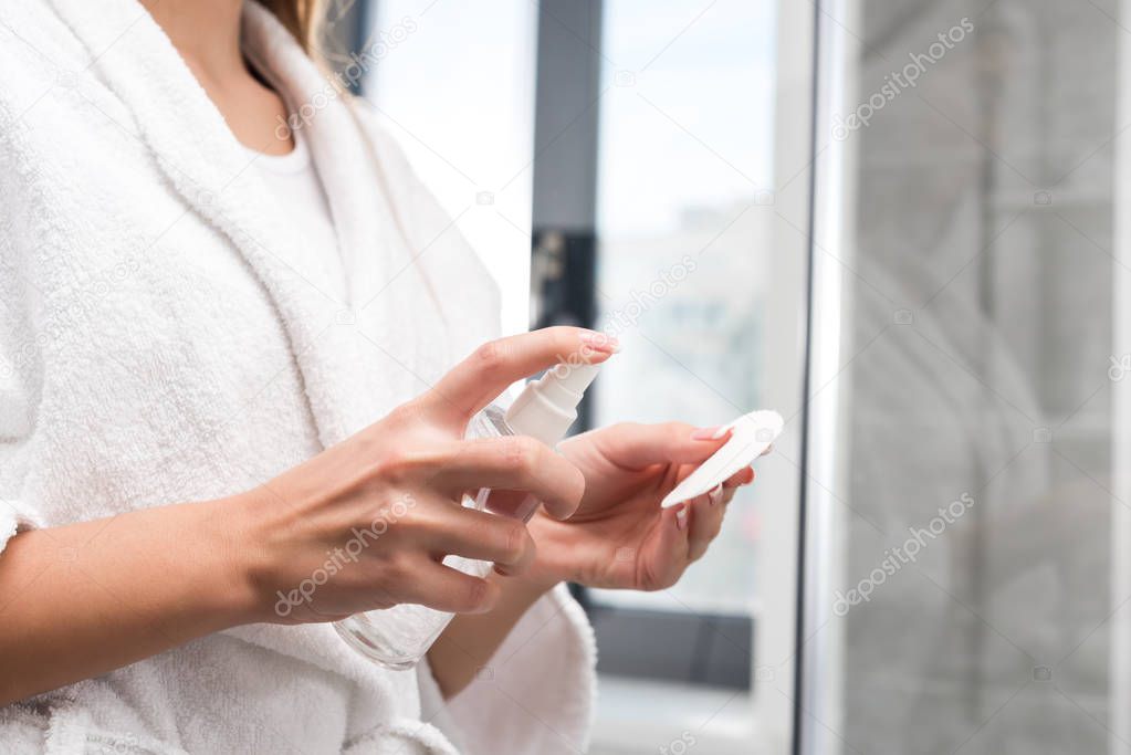 woman applying lotion on cotton pad 